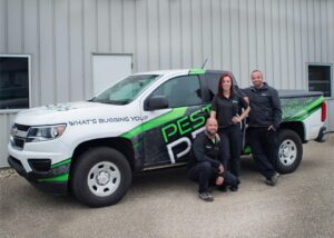 Three Pest Pros technicians posing and smiling in front of a Pest Pros truck.