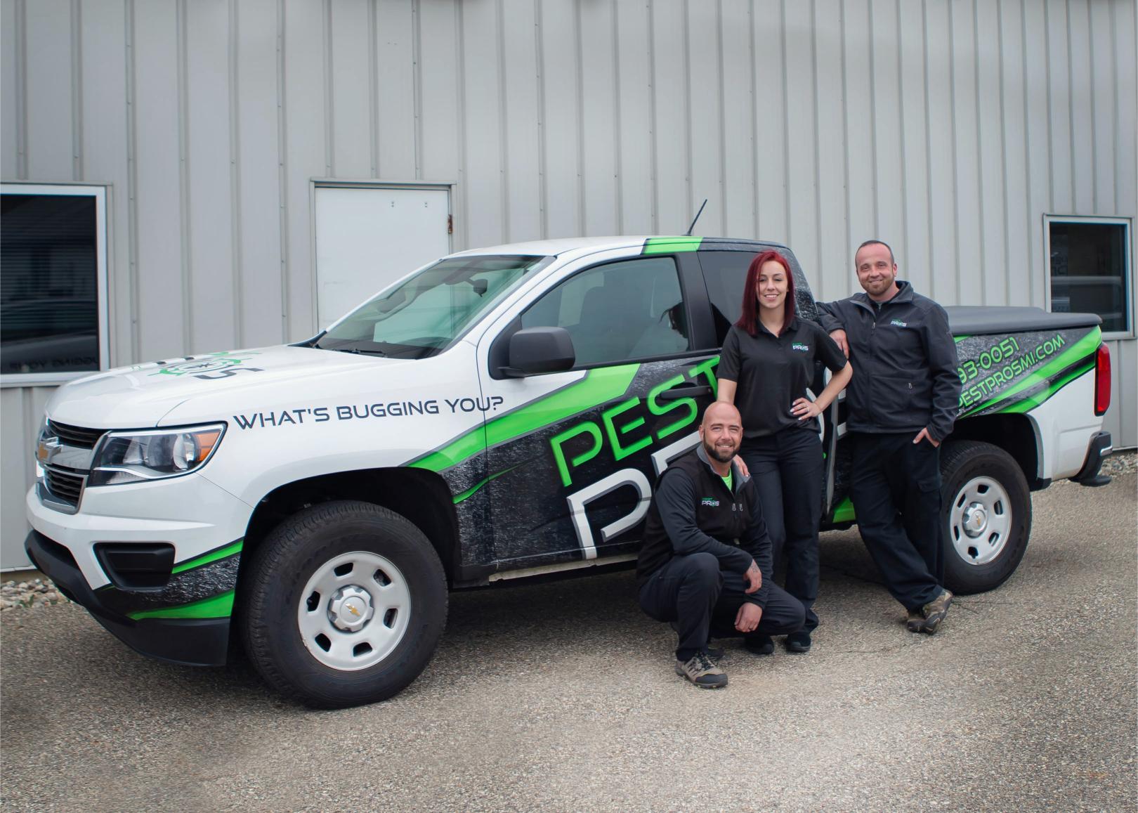 Three Pest Pros technicians posing and smiling in front of a Pest Pros truck.