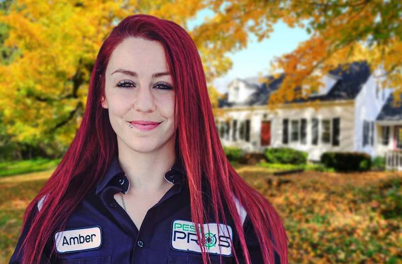 Close up of one of our Pest Pros technicians in her work uniform, in front of a home.