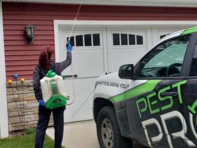 One of our technicians spraying treatment on the exterior of a house standing next to one of our Pest Pros vehicles.