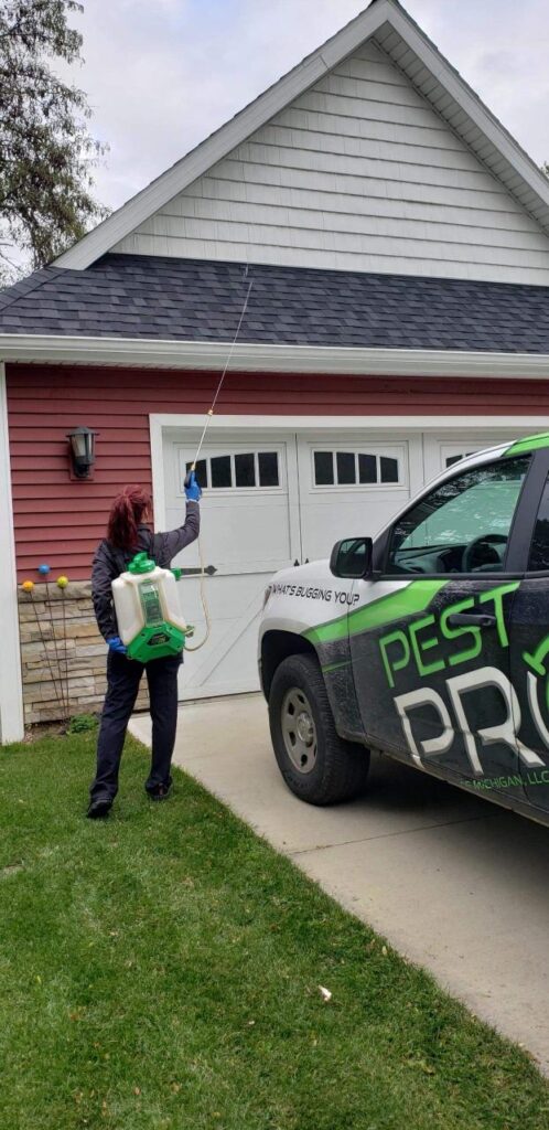 One of our technicians spraying treatment on the exterior of a house standing next to one of our Pest Pros vehicles.